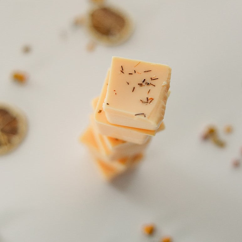 Orange Grove wax melt cubes stacked with dried botanicals on white background